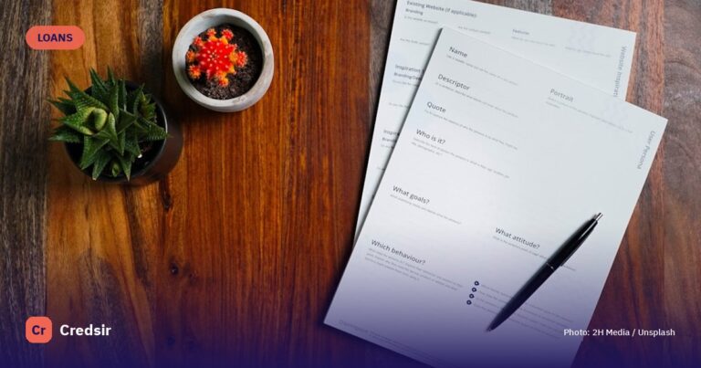 A wooden table topped with papers and a pen — cover photo for Credsir’s Gold Loan guide