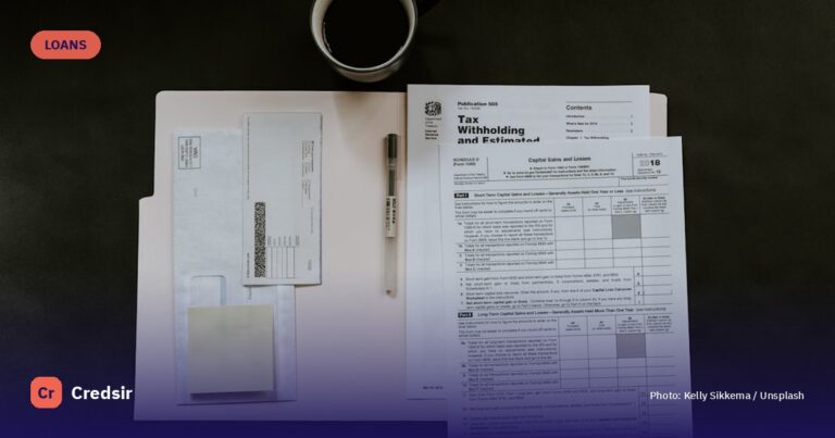 Tax forms, a pen, and a coffee mug on a dark desk — cover photo for Credsir’s Education Loan EMI Calculator guide
