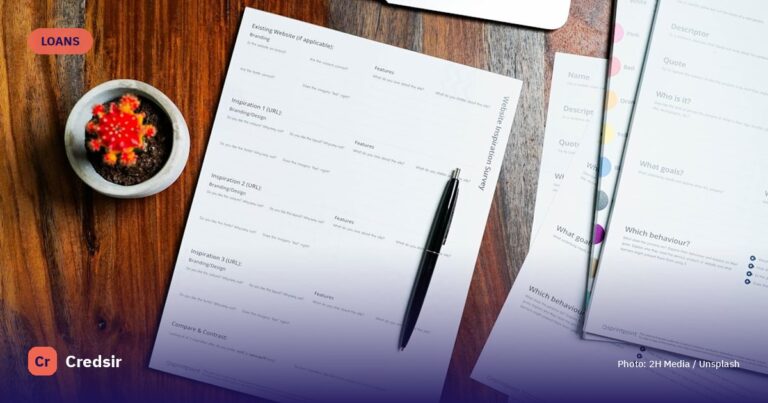 A wooden table topped with papers and a pen — cover photo for Credsir’s Education Loan Interest Rates guide