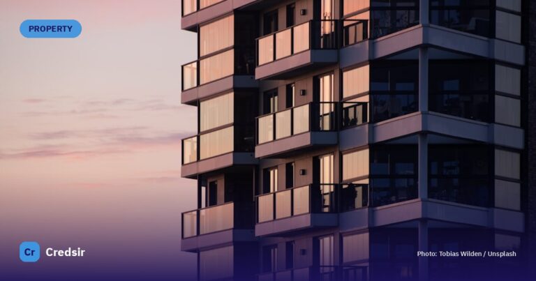 A modern apartment building with glass balconies reflecting a soft pink sky — cover photo for Credsir’s HRERA Haryana guide